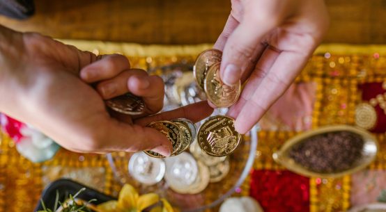 Hands counting gold coins for investing in gold monetization scheme