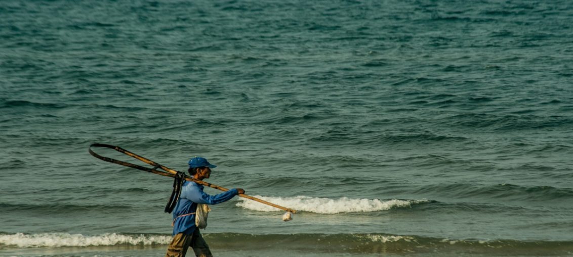 Fisherman walking on a beach, highlighting Assam's support for coastal livelihoods