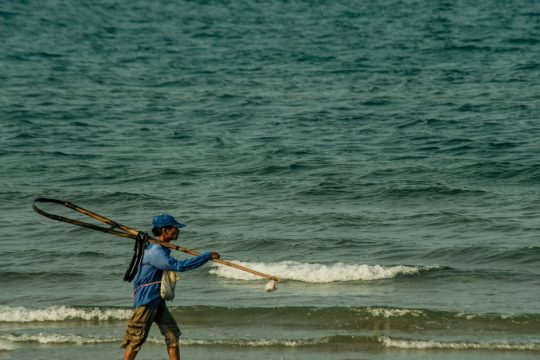 Fisherman walking on a beach, highlighting Assam's support for coastal livelihoods